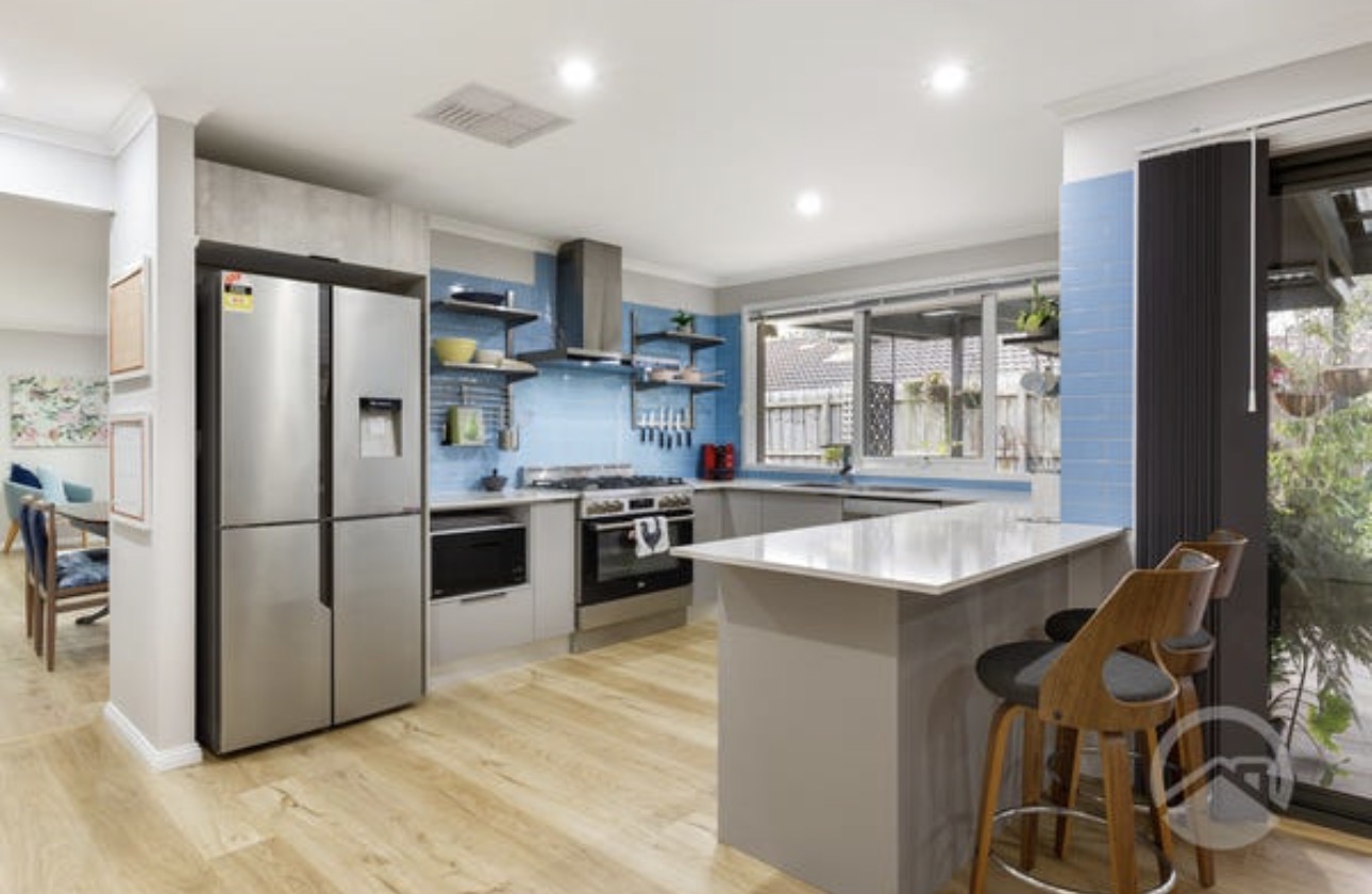 The open-plan kitchen at Cranbourne North House with a blue tiled splashback