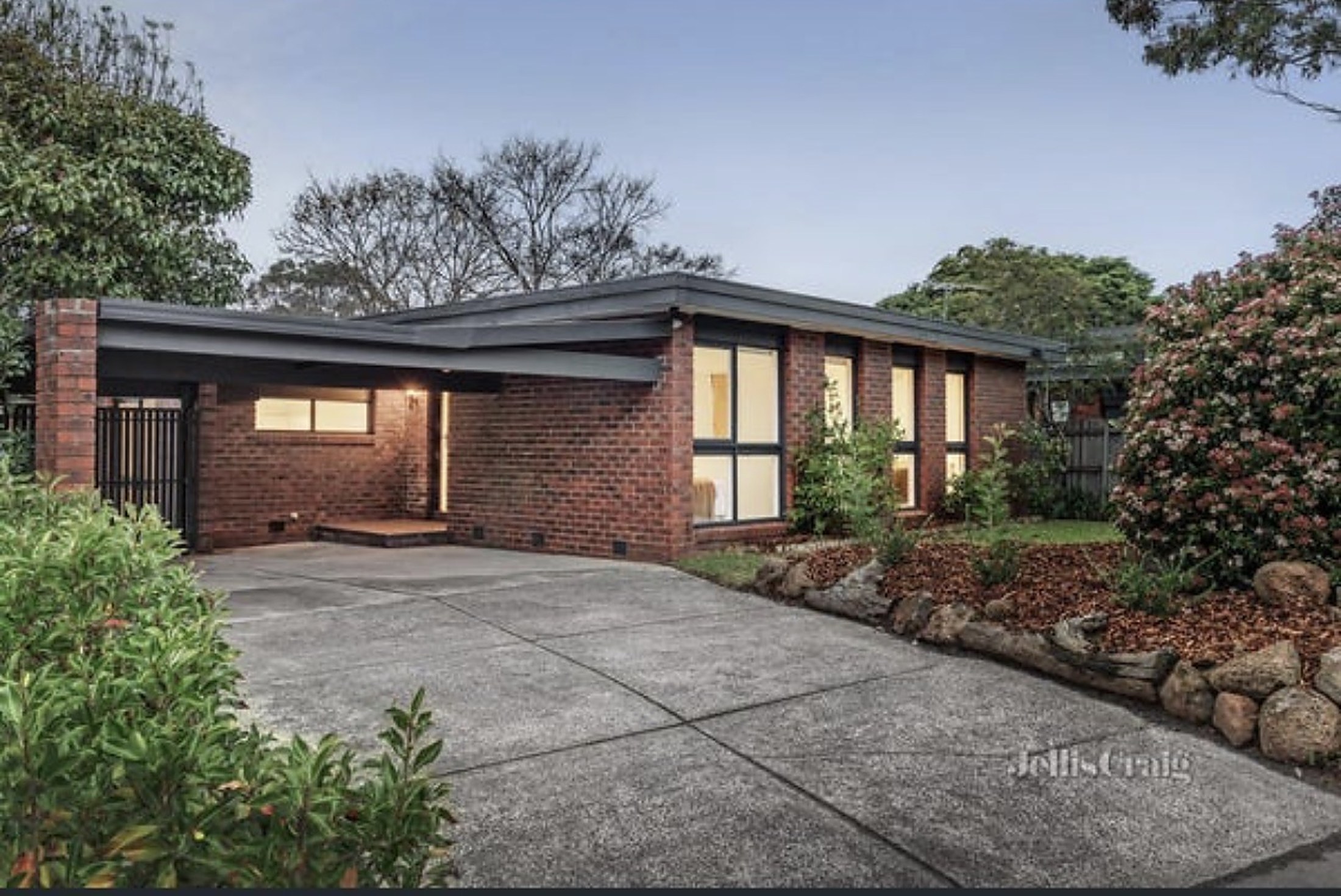 The front of Viewbank House at dusk, with its brick facade and landscaped garden