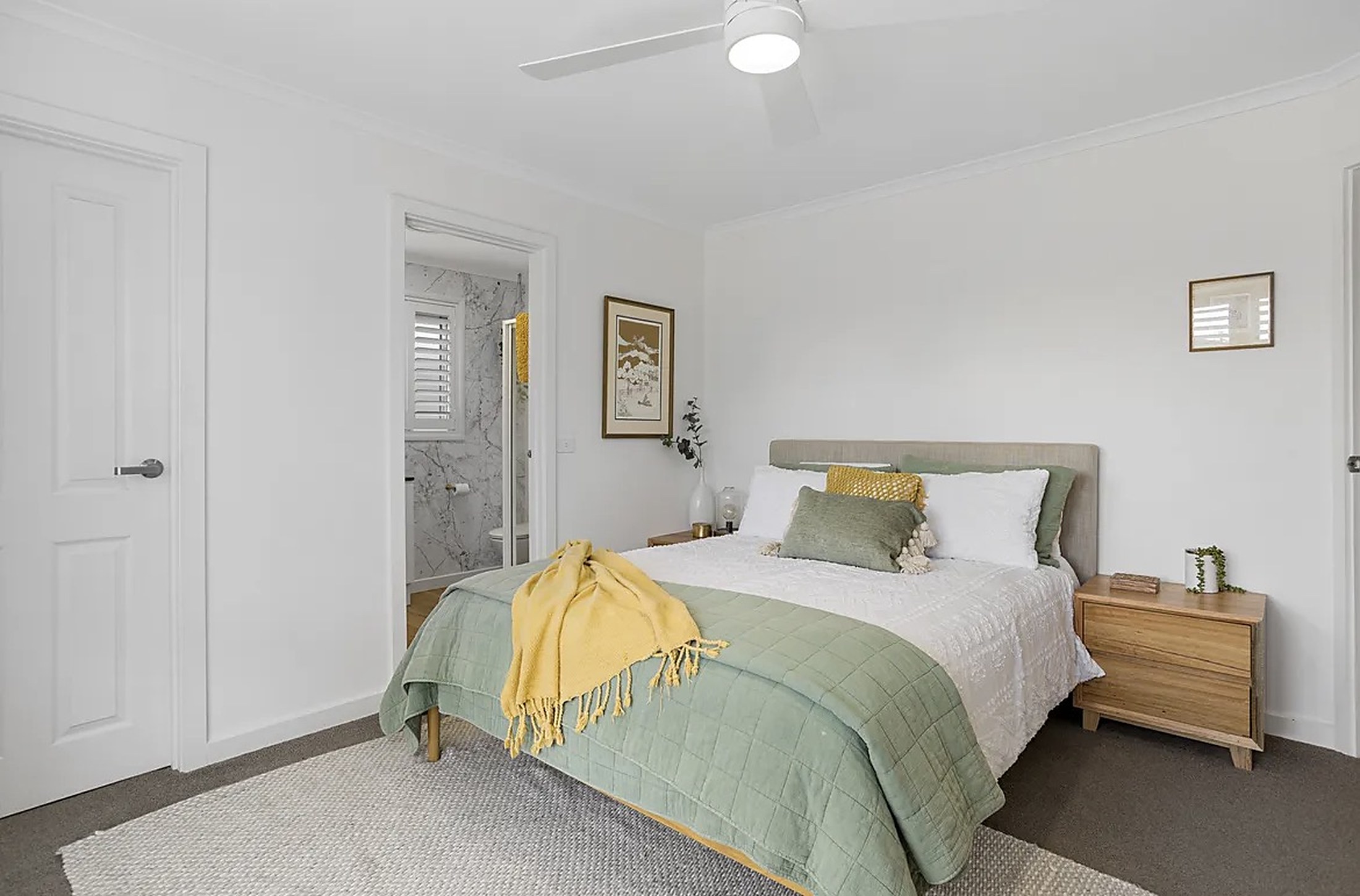A light, calm bedroom at Mornington House with soft green and white bedding