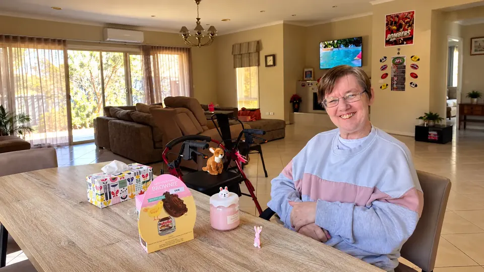 A woman smiling at a table in a welcoming open-plan home