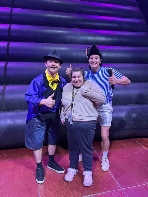 A woman smiling with two performers at a live show