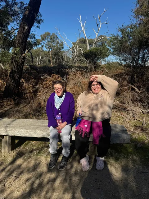 Two women enjoying a sunny break on a woodland bench