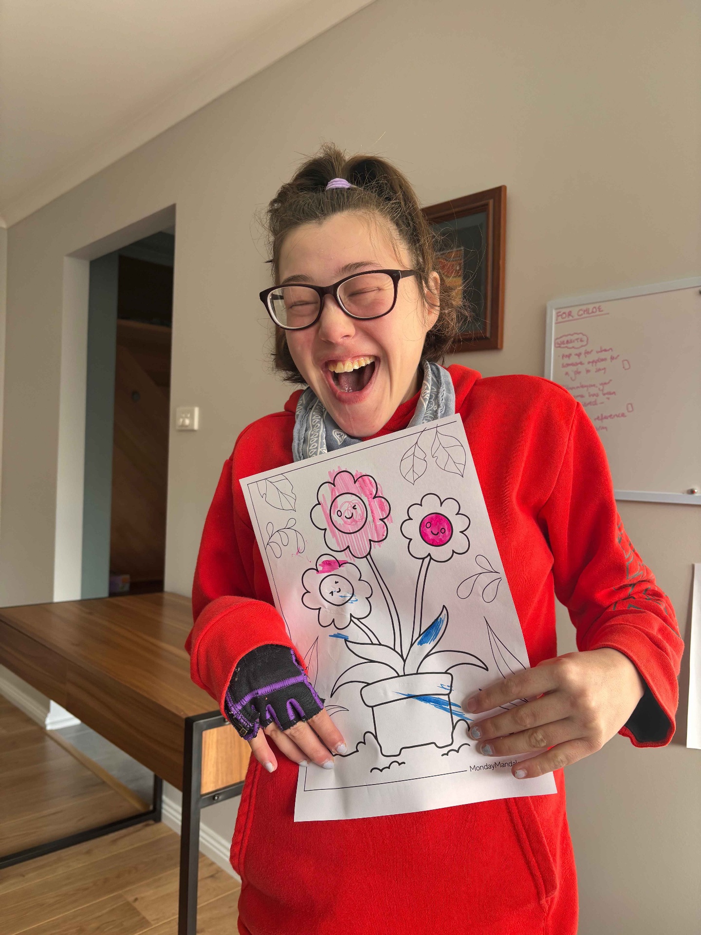 A woman proudly sharing her colourful flower artwork at home