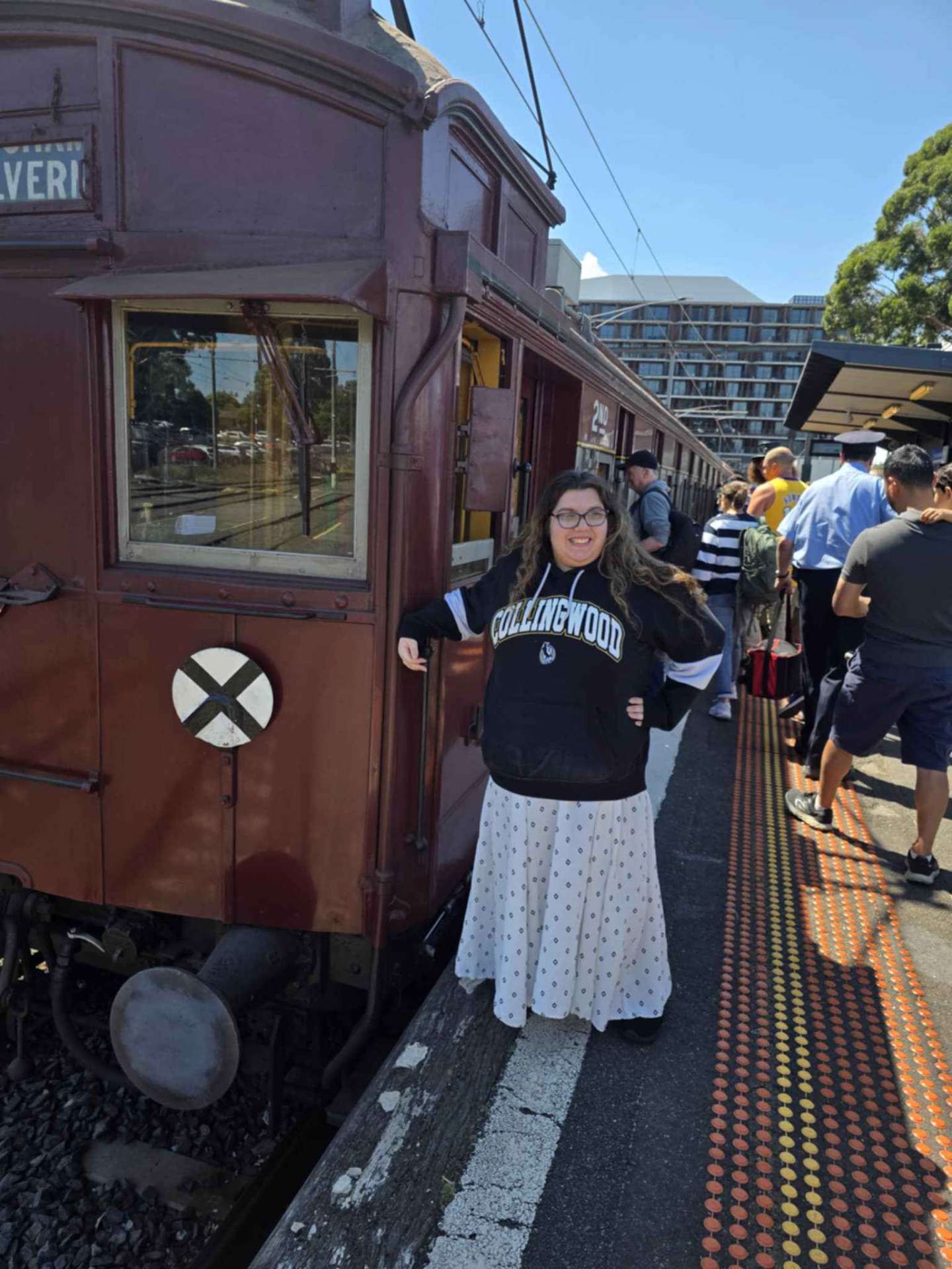 A smiling woman beside a heritage train on an outing